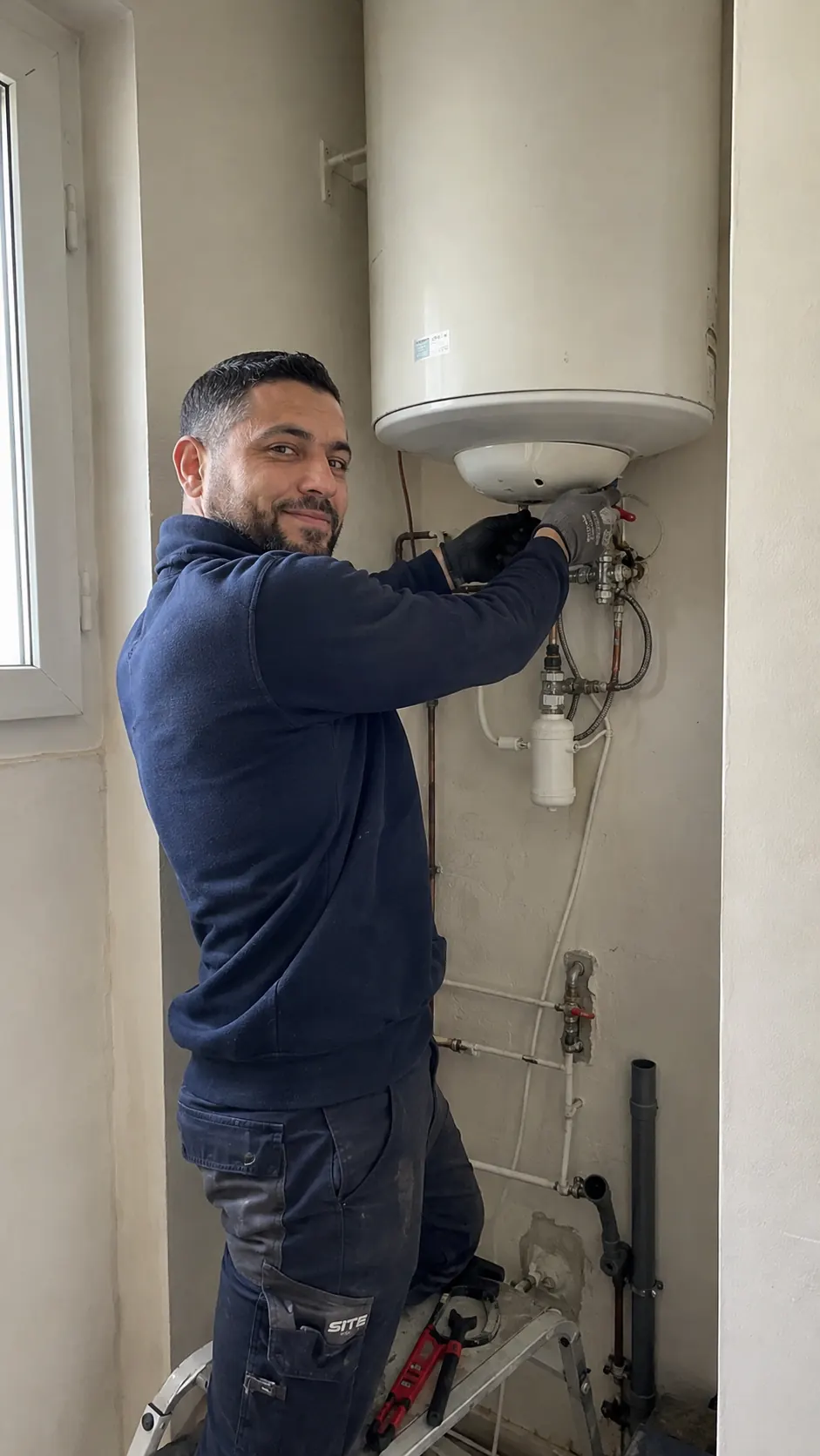 Hamed, plombier à son compte, en intervention sur un chauffe-eau